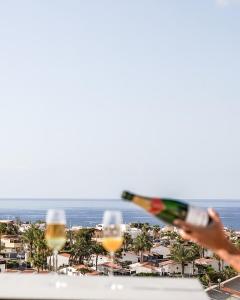 a person holding a bottle of wine and two glasses at Cornisa Apartments in Patalavaca