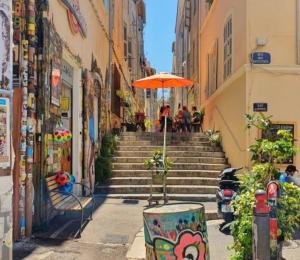 een trap met een oranje paraplu en mensen aan tafels bij Le bohème du Panier in Marseille