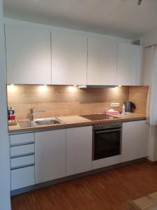 a kitchen with white cabinets and a sink at Ferienwohnung BaMBi in Prien am Chiemsee