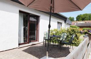 a patio with a table and chairs and an umbrella at Am Küstenwald in Ostseebad Koserow