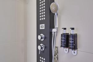 een douche in een badkamer met een douchekop bij Hotel Gatsby by HappyCulture in Chassieu