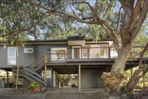 una casa con un grande albero di fronte di Whispering Gums - Ocean Views, Pet Friendly, EV UNIT 7kW for electric cars, Sleeps 7 a Lorne