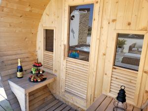 una sauna de madera con banco y una botella de vino en La Villa Thelma 5 étoiles, piscine, sauna et jacuzzi en Granville