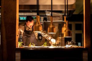 a chef preparing food in a restaurant kitchen at Erfgoed Bossem in Lattrop