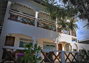 a white house with palm trees in front of it at Cocolala Beach House in Nungwi