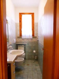 a bathroom with a sink and a toilet and a window at La casa di Pane in Follonica