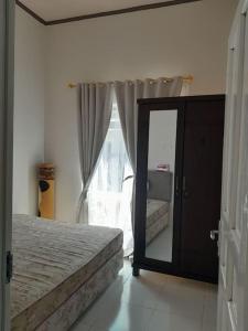 1 dormitorio con cama, espejo y ventana en Bumi Dieng Indah Residence en Kalianget