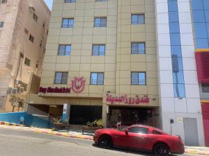 a red car parked in front of a building at Rose Al Medina Hotel in Medina