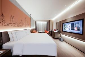 深セン市にあるUrCove by HYATT Shenzhen Luohuの大型ベッド1台、薄型テレビが備わるホテルルームです。