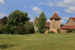 un antiguo edificio de ladrillo con una torre en un campo en les Tours de Bombel, en Saint-Amand-de-Coly