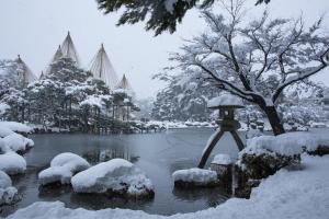 ein schneebedeckter Park mit einem Teich und einem Vogelhaus in der Unterkunft Guesthouse Namaste in Kanazawa