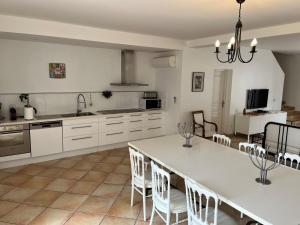 una cucina con mobili bianchi, tavolo e sedie di Les Terrasses Binel à Ronsac ad Aigrefeuille