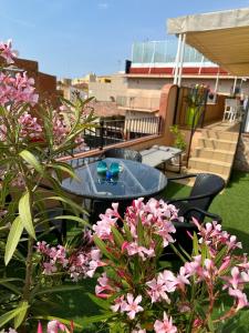 un patio con una mesa y algunas flores rosas en Royal Inn Aparthotel en Lloret de Mar