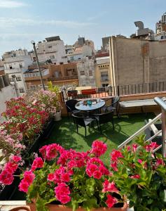 een balkon met roze bloemen en een tafel en stoelen bij Royal Inn Aparthotel in Lloret de Mar
