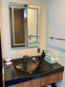 een badkamer met een zwarte wastafel en een spiegel bij Sky Blue Villa沖縄 in Jima