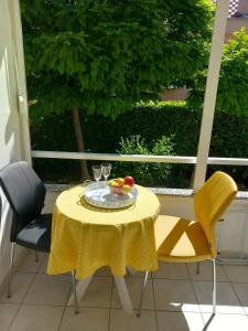 een tafel met een fruitschaal en twee gele stoelen bij Studio apartman MARIJA in Petrcane
