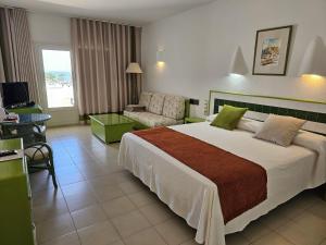Hotel Puntazo II في موجاكار: غرفة فندقية بسرير كبير واريكة