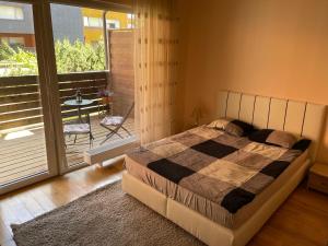 a bedroom with a bed and a balcony with a table at Cozy Apartment, Jaukus Butas Centre, internet in Klaipėda