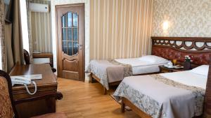 a hotel room with two beds and a desk at Hotel Lviv in Lviv