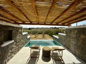 a swimming pool with two chairs and a wooden roof at Abelos Mykonos in Mýkonos City