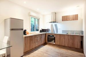 uma cozinha com armários de madeira e um frigorífico em Maison individuelle avec piscine privative. em Saint-Médard-en-Jalles