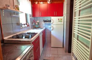 a kitchen with red cabinets and a white refrigerator at Emerald Bell Cottage - Smaragdni Zvonček 