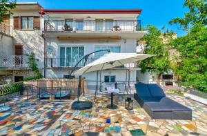 德拉马利Apartman Draga的一座带遮阳伞和沙发的庭院