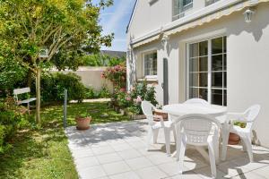 un patio con una mesa blanca y sillas en Magnolia - Charmante maison avec jardin, en Nantes