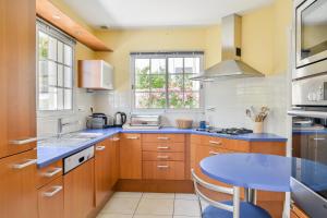 a kitchen with wooden cabinets and a blue table at Magnolia - Charmante maison avec jardin in Nantes