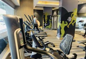 - une salle de sport avec des rames de vélos d'exercice et un homme en arrière-plan dans l'établissement Black Pearl DLF My Pad, à Lucknow