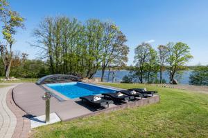 a swimming pool with a row of black chairs around it at Reketijos Dvaras in Reketija