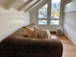 ein Sofa mit zwei Kissen in einem Zimmer mit Fenster in der Unterkunft Ferienwohnung BuchtSpiez in Spiez