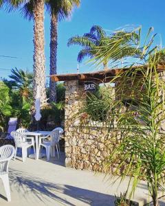 a restaurant with a table and chairs and palm trees at Case Vacanza Zeus in Trappeto