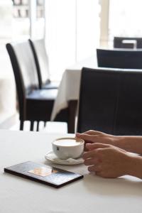 una persona sentada en una mesa con una taza de café en Hotel Lviv, en Leópolis