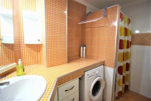 uma casa de banho com um lavatório e uma máquina de lavar roupa em Precioso apartamento con piscina WiFi em La Pobla de Farnals