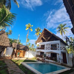 a villa with a swimming pool and palm trees at Mambo Cabana in Pwani Mchangani