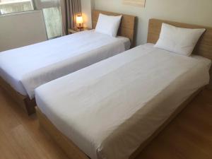 two beds in a room with white sheets and pillows at Rhodes Kagurazaka in Tokyo
