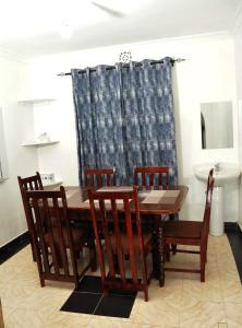 a dining room with a wooden table and chairs at Pacific Homes @milimani court, kakamega in Kakamega