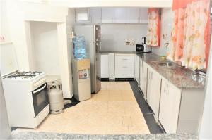 a kitchen with white appliances and a tile floor at Pacific Homes @milimani court, kakamega in Kakamega