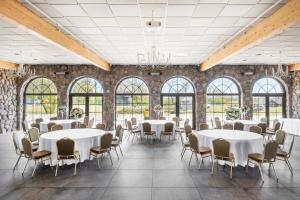 a room with white tables and chairs and windows at Reketijos Dvaras in Reketija