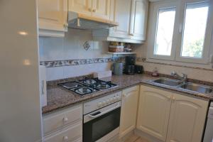 a kitchen with white cabinets and a stove and a sink at Casa Mandarina in Els Poblets