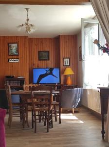 a dining room with a table and chairs and a tv at La Lisière Appartement 2 chambres in Revin