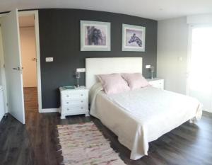 ein Schlafzimmer mit einem weißen Bett mit rosa Kissen in der Unterkunft Casa Sartages in Ribadumia