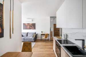a kitchen with white cabinets and a living room at Žalia kopa Vilnius Paupys in Vilnius +17 photos