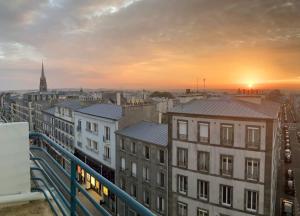 d'un balcon offrant une vue sur la ville au coucher du soleil. dans l'établissement Vue mer / Jaurès-Centre-Ville / Appart Lumineux, à Brest