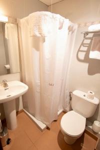 a white bathroom with a toilet and a sink at Pensio La Creu in Esterri d'Àneu