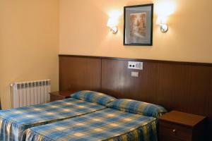 a hotel room with a bed with a plaid blanket at Pensio La Creu in Esterri d'Àneu