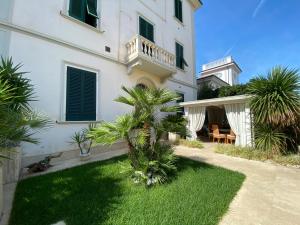 a large white building with a yard with palm trees at Villa Rosy in San Vincenzo