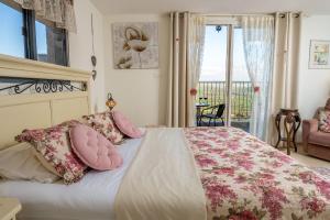 a bedroom with a bed with pink pillows and a balcony at Suite Kolibri in Galilee in Semadar