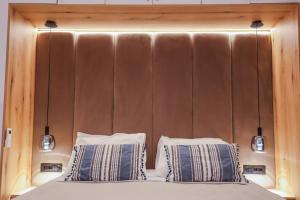 ein Kopfteil aus Holz mit zwei Kissen auf einem Bett in der Unterkunft City Compass Luxury Suites in Rhodos (Stadt)